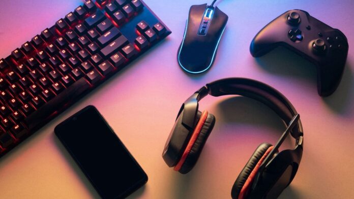 black-gaming-equipment-image1 Headphones, mouse, keyboard and phone on a desk with pink lighting