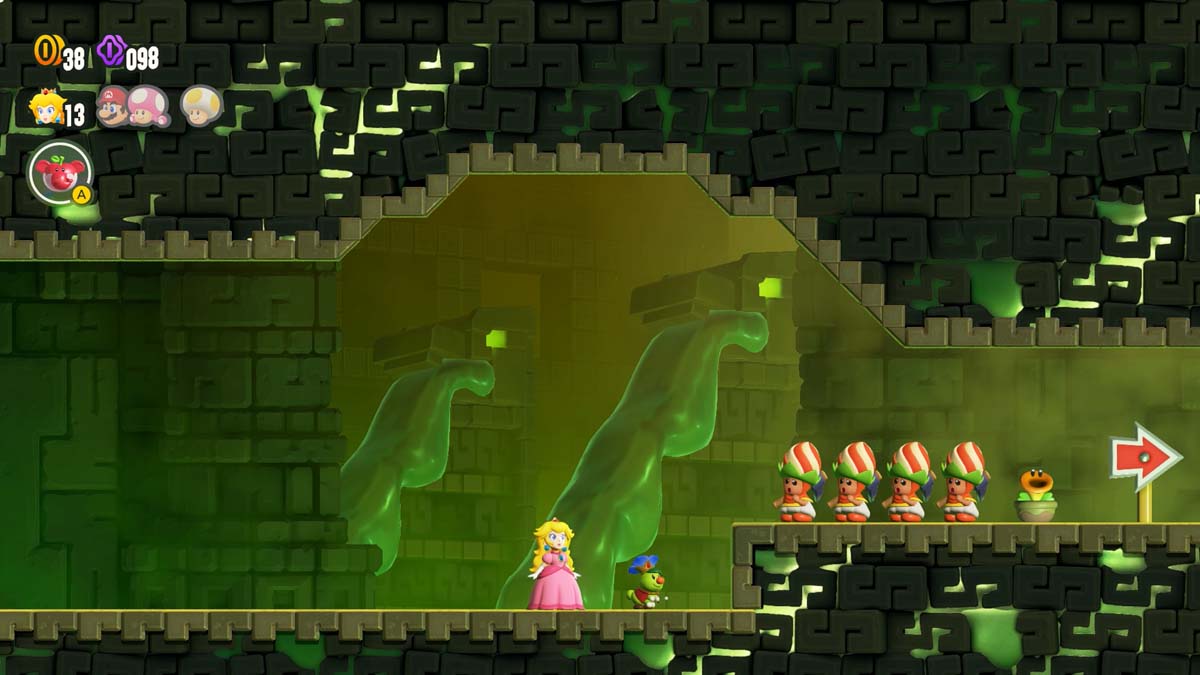 Super Maro Bros Wonder Princess Peach and a group of characters with protective helmets look toward a direction indicated by an arrow in a ghostly green-tinged castle corridor.